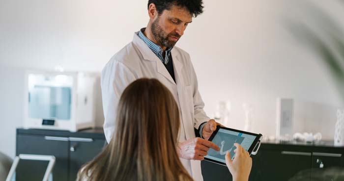 Arzt zeigt Patientin Diagnose auf einem Tablet